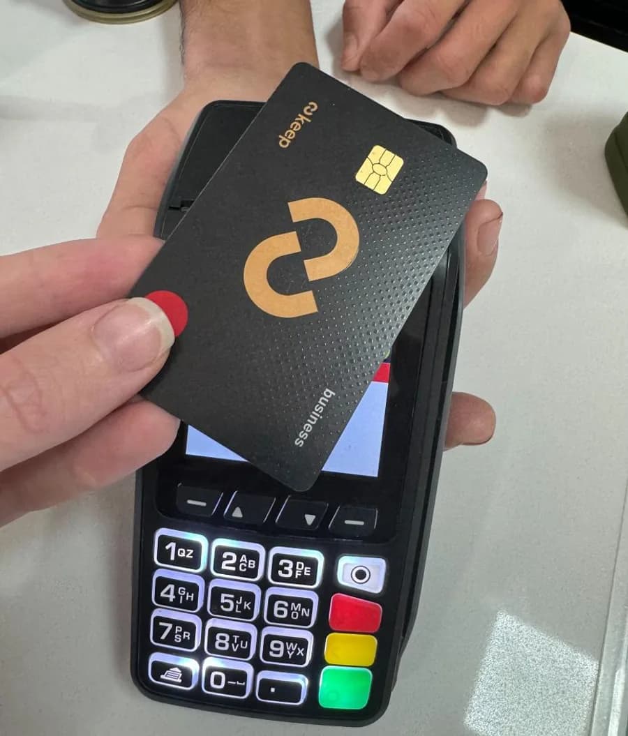 A Keep business Mastercard being tapped against a contactless payment terminal at a checkout