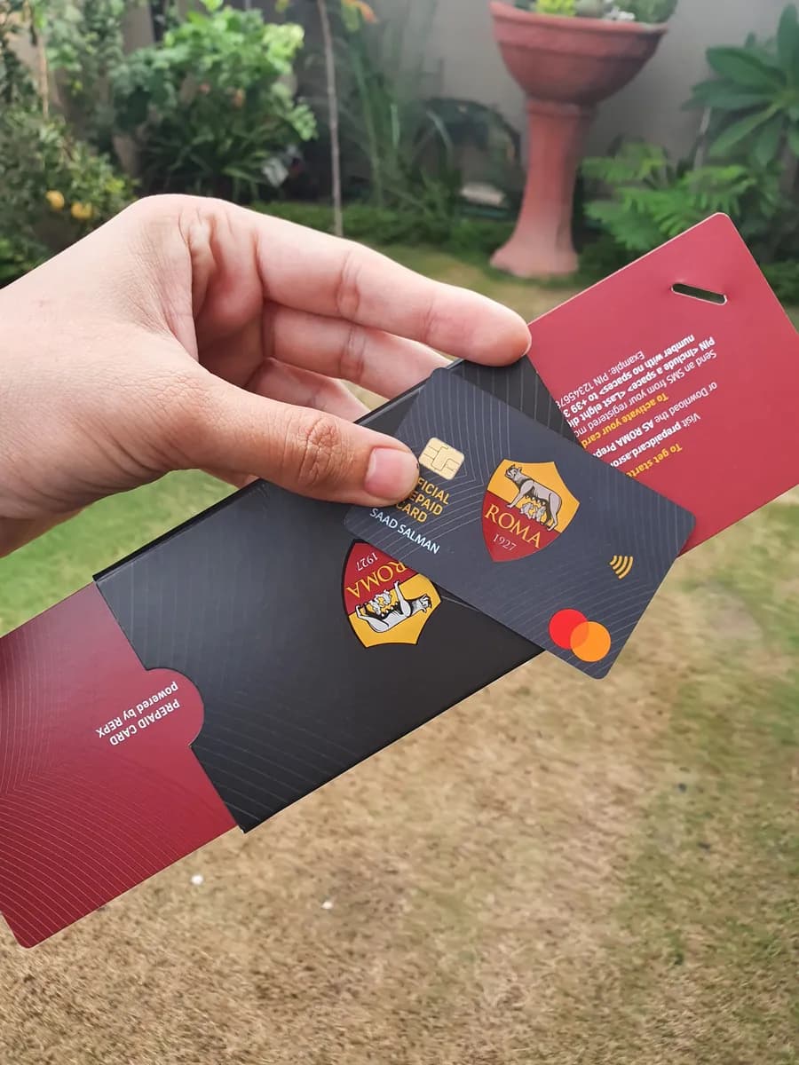 The AS Roma card sliding out of its carrier, printed with prepaid card powered by REPX